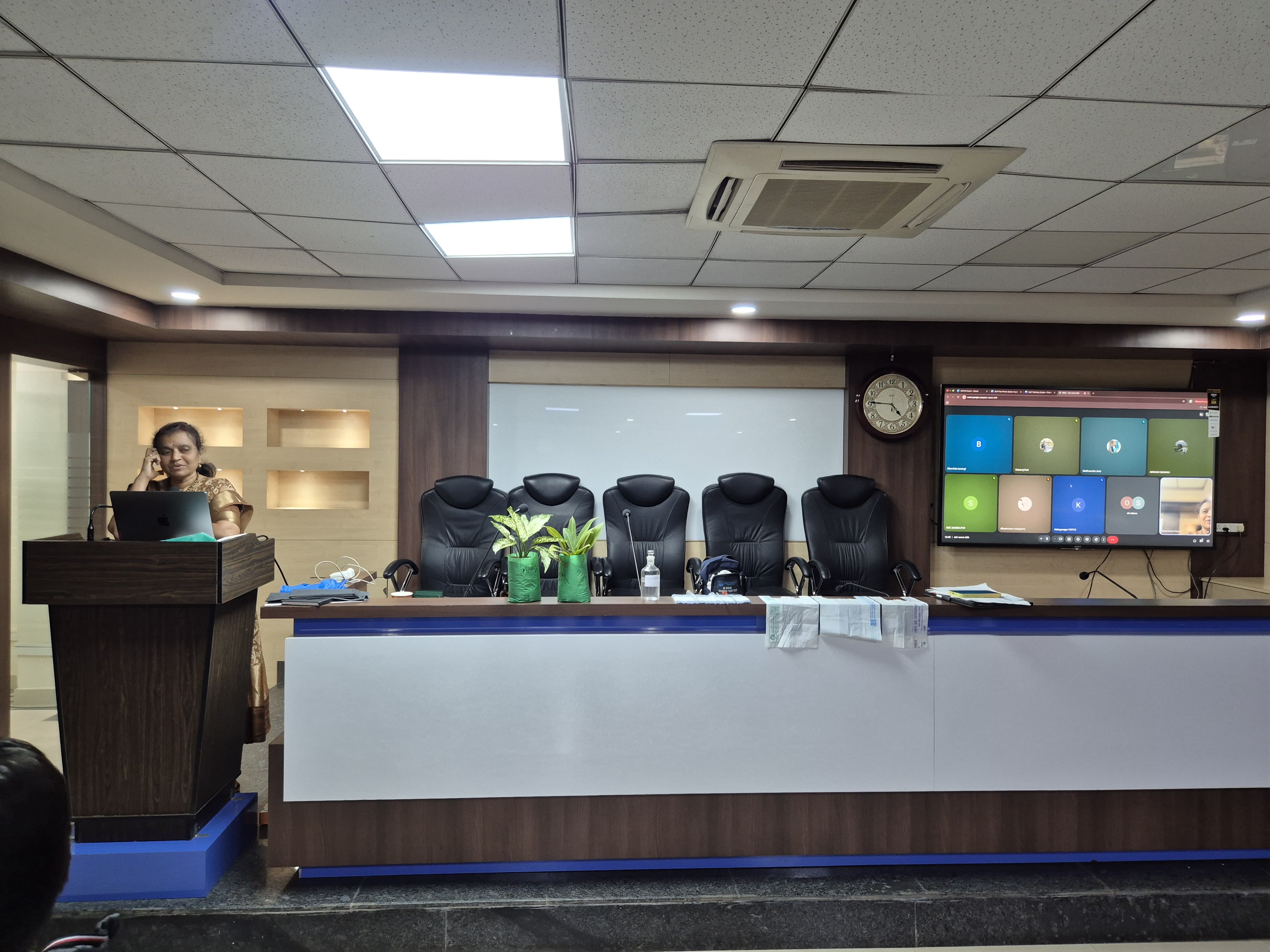 Speaker at podium with online participants